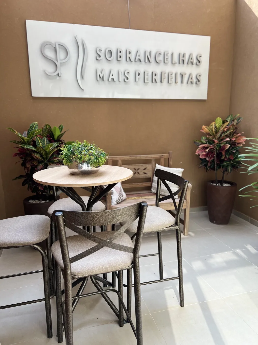 Recepção com mesa, cadeiras, plantas e o logo SP na parede